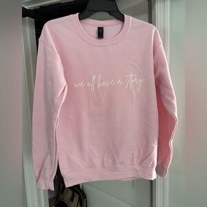 NWT “we all have a story” bright pink sweatshirt with white writing